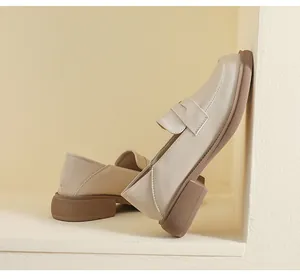 Detail view of cream leather loafers with thick brown rubber sole and slip-on design