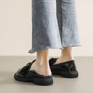 Glanzende zwarte lakschoenen met strik en gouden gesp detail op model