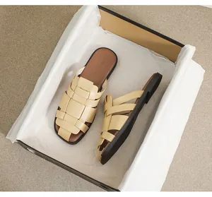 Top view of beige woven flat sandals with brown insoles inside a premium shoebox