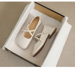 Draufsicht auf cremefarbene Mary Jane Schuhe mit Doppelriemen und Goldschnallen