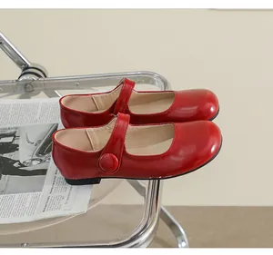 Close-up of red patent leather Mary Jane shoes with strap on a newspaper background