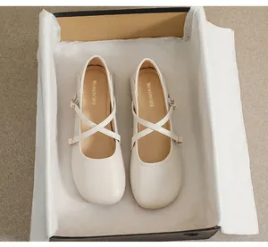 Draufsicht auf cremefarbene Mary-Jane-Schuhe mit Kreuzriemen im Marken-Schuhkarton