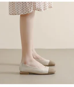 On-foot view of cream and brown two-tone square toe flat shoes with polka dot dress