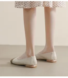 Rear view of elegant cap-toe flat shoes with cream leather and wood-textured low heel