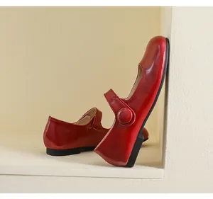 Detail view of red leather Mary Jane flat with matte finish and buckle strap