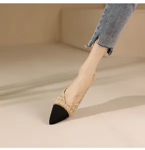 Close-up of pointed toe flat shoes in beige tweed with black tip and gold chain detail
