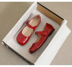 Detailed top view of shiny red patent leather Mary Jane shoes in a black gift box