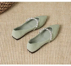 Detailed view of light green pointed flats with pleated texture and pearl strap accent
