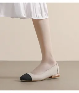 Close-up of beige lychee leather flat shoes with black cap toe and wood grain heel