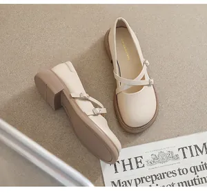 Close-up of beige Mary Jane shoes with double crisscross straps and metal buckles on a rug