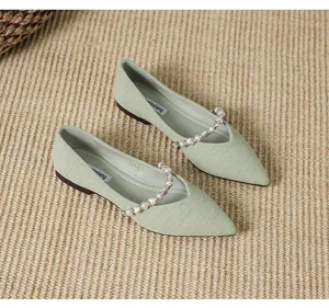 Detail of light green pointed toe flat shoe with delicate pleated texture and pearl strap