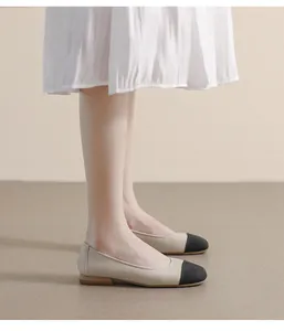 Close-up of elegant beige leather flat shoes with black toe cap and lychee texture detail