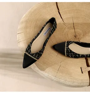 Top view of black and gold tweed pointed-toe flat shoes with metal chain detail