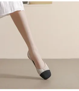 Detail of two-tone flat ballet shoes featuring beige leather and a black textured toe cap