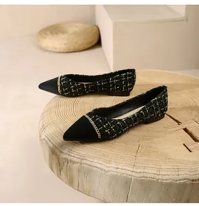 Close-up of black tweed pointed toe flats with elegant gold chain detail and suede trim
