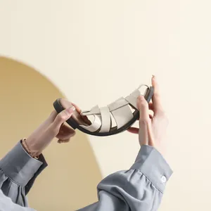 Flexible cream woven flat sandals with a soft sole shown bending to demonstrate comfort