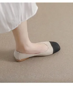 Detail view of two-tone square toe flat shoes with beige leather and black cap toe