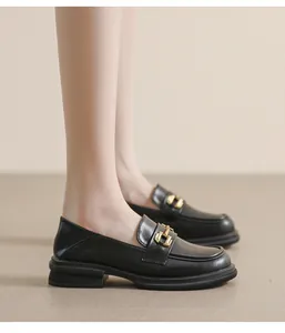 Close-up of black platform loafers with gold chain buckle detail and leather texture