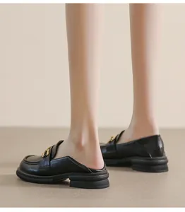 Detail view of black leather loafers with gold buckles and platform rubber soles