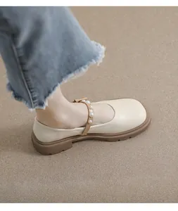 Detailed close-up of cream Mary Jane platform shoes with pearl strap and chunky sole