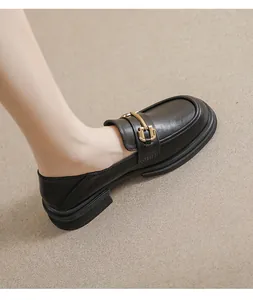 Detail of black leather platform loafer featuring a golden metal buckle and non-slip sole