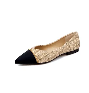 Close-up of pointed-toe flat shoe with black satin tip and elegant gold chain detail
