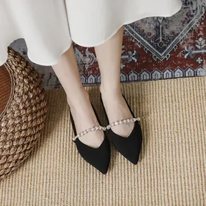Elegant black knit pointed-toe flat shoes with pearl strap shown from a top-down view