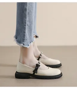 Detail of cream Mary Jane shoes featuring black bow strap with pearls and platform sole
