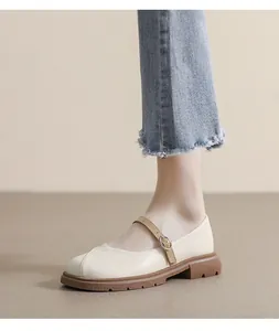 Détail d'une chaussure Mary Jane beige avec semelle crantée et bride en cuir marron