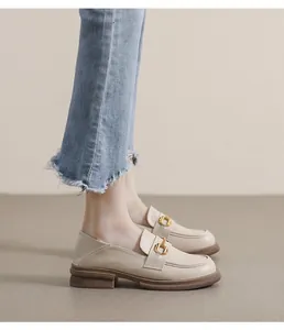 Detail of cream platform loafers with gold horsebit buckle and blue frayed jeans