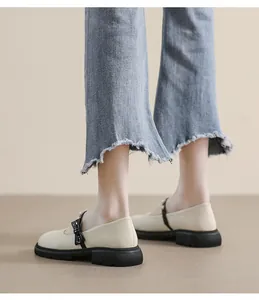 Close-up of white Mary Jane shoes with black bows and pearls on flared jeans