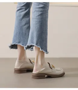 Detailed side view of beige platform loafers with gold buckle and brown rubber sole
