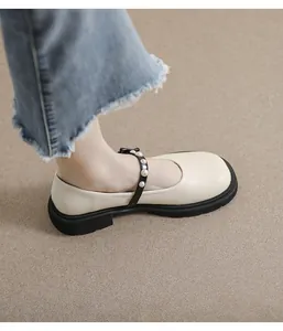 Close-up of beige Mary Jane shoes with pearl-embellished black straps and platform soles