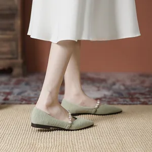 Pale green pointed-toe flat shoes with pearl strap and vertical striped texture on model