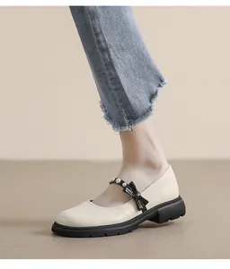 Detail of cream Mary Jane shoes featuring pearl accents, black bow, and platform sole
