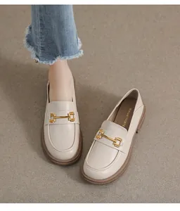 Close-up of off-white leather loafer featuring a golden horsebit metal buckle detail