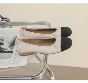 Detail view of two-tone beige and black leather ballet flats on glass surface
