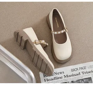 Detail of beige Mary Jane shoe with elegant pearl strap and bow on platform sole