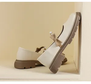 Close-up of cream Mary Jane shoe with pearl bow detail and thick brown platform sole