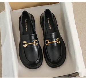 Close-up of black leather platform loafers with gold metal horsebit and brand insole