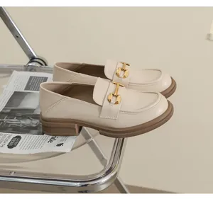 Detail of beige leather loafers with gold hardware and thick rubber soles in a studio setting