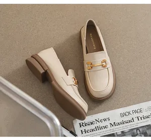 Close-up of beige platform loafers featuring gold horsebit detail and soft leather texture
