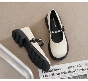Detail of beige Mary Jane shoe with pearl strap, black bow and chunky platform sole