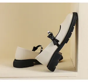 Detail of platform Mary Janes featuring a glossy bow with pearl accent and thick tread sole