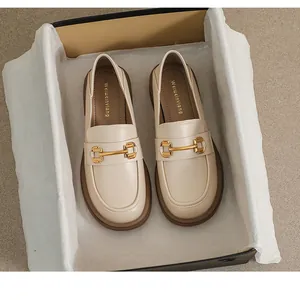 Top view of beige platform loafers with gold horsebit hardware in a black shoebox