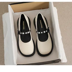 Detailed top view of cream Mary Jane shoes with pearl-embellished black patent leather straps