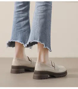 Vista detallada de mocasines beige con plataforma, suela track marrón y vaqueros