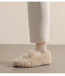 Close-up of beige faux lamb wool flat shoes with soft fleece texture and button detail