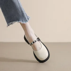 Platform Mary Jane shoes in beige with black bow and pearl detail worn with denim