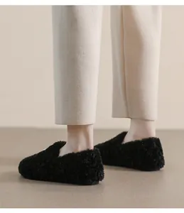 Close-up of black fuzzy loafers featuring textured plush material and a soft flat sole